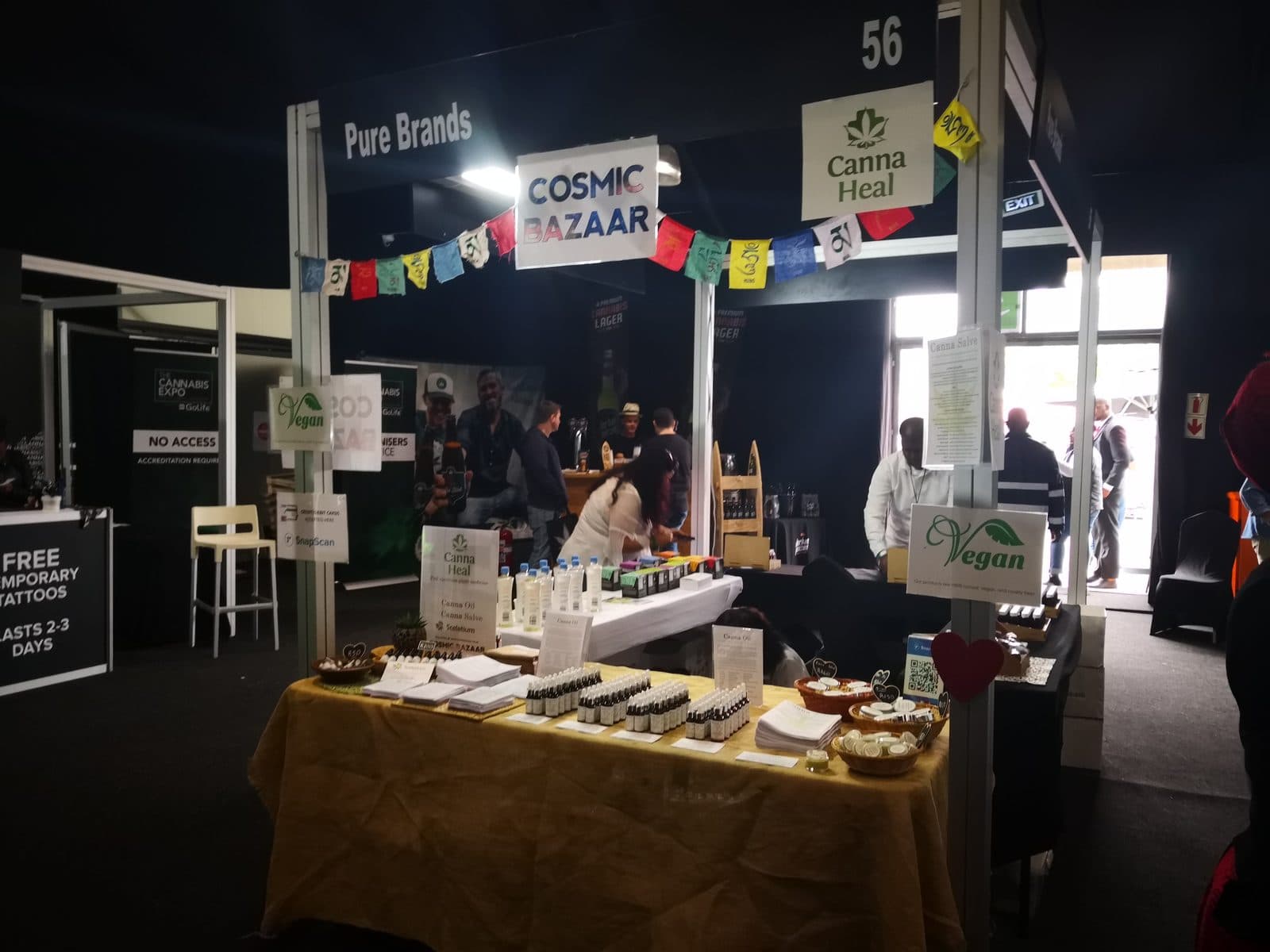 The Cosmic Bazaar and Canna Heal stand at the Cannabis Expo, prayer flags over tables of tinctures.