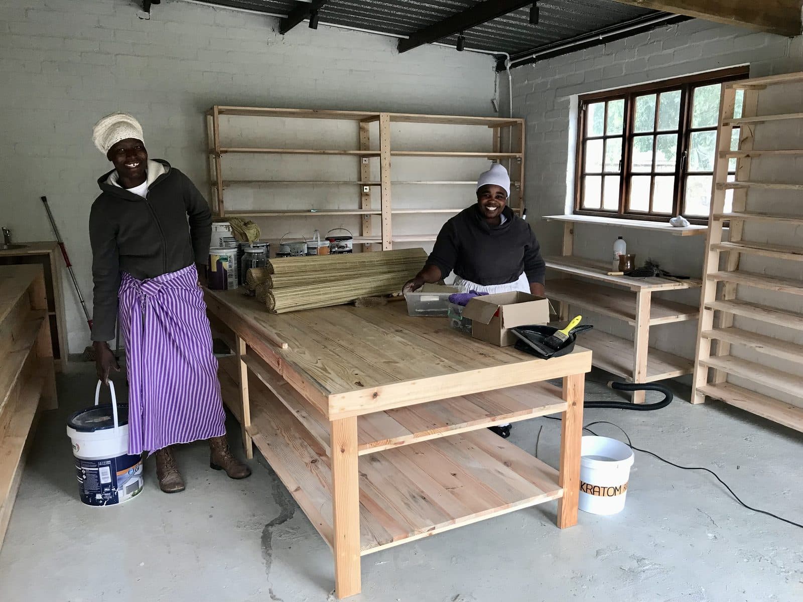 Two smiling team members building the shop at Earth Hub.