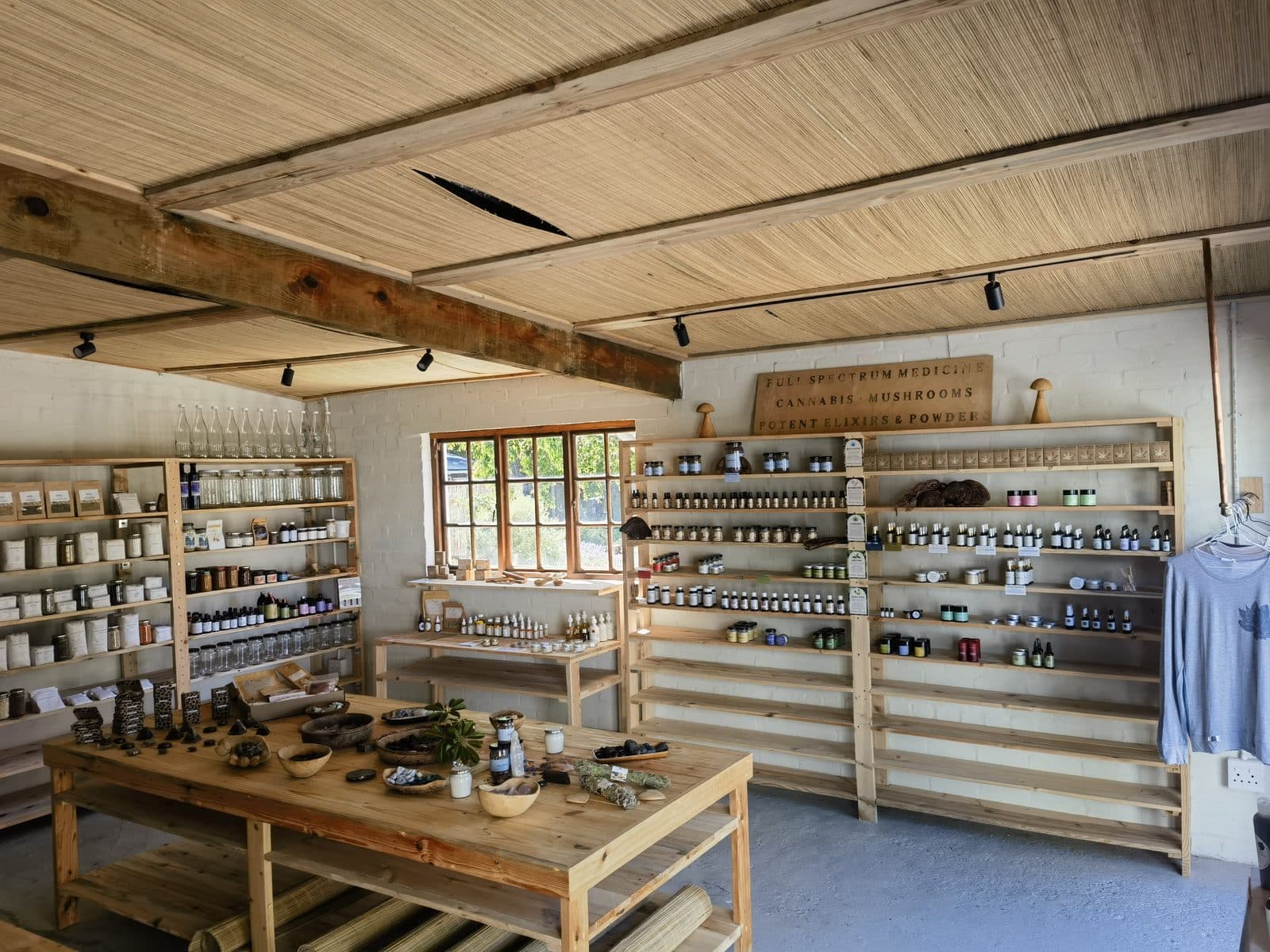 Inside the Cosmic Bazaar shop at Earth Hub — reed ceiling, timber shelves and the apothecary wall.